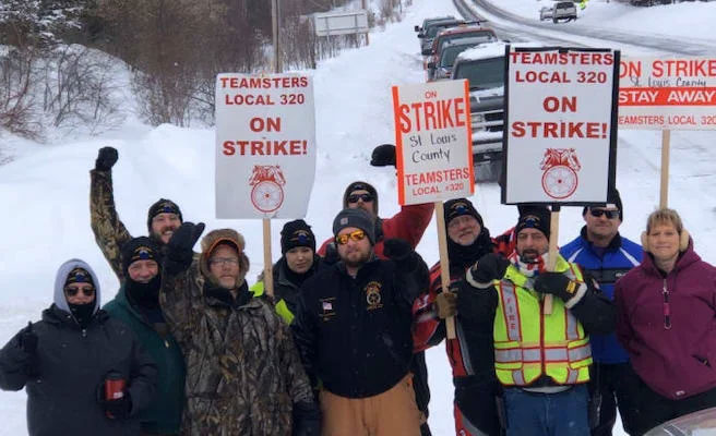 strike workers in the snow holding up picket signs